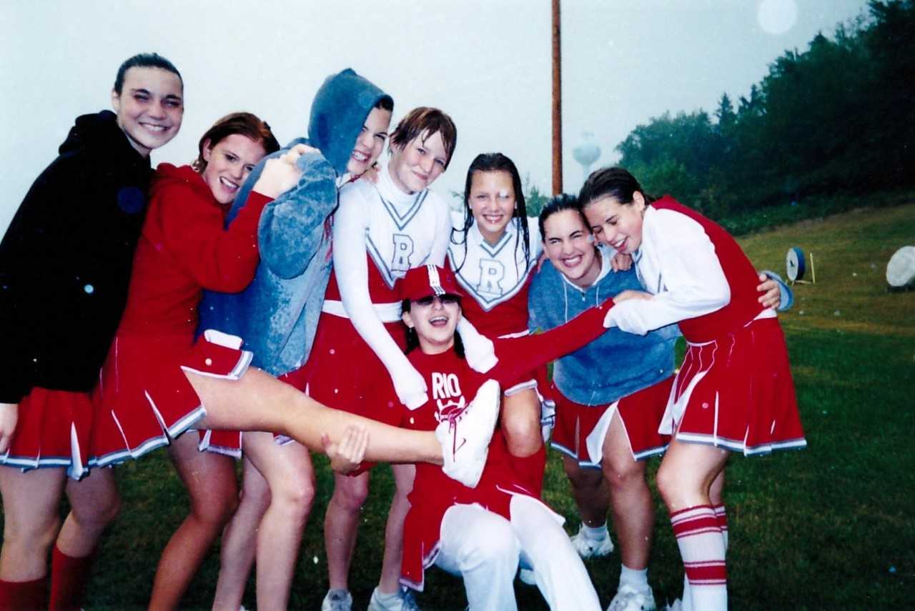 Maria, during her high school exchange, posing with her cheerleading squad on a sports field