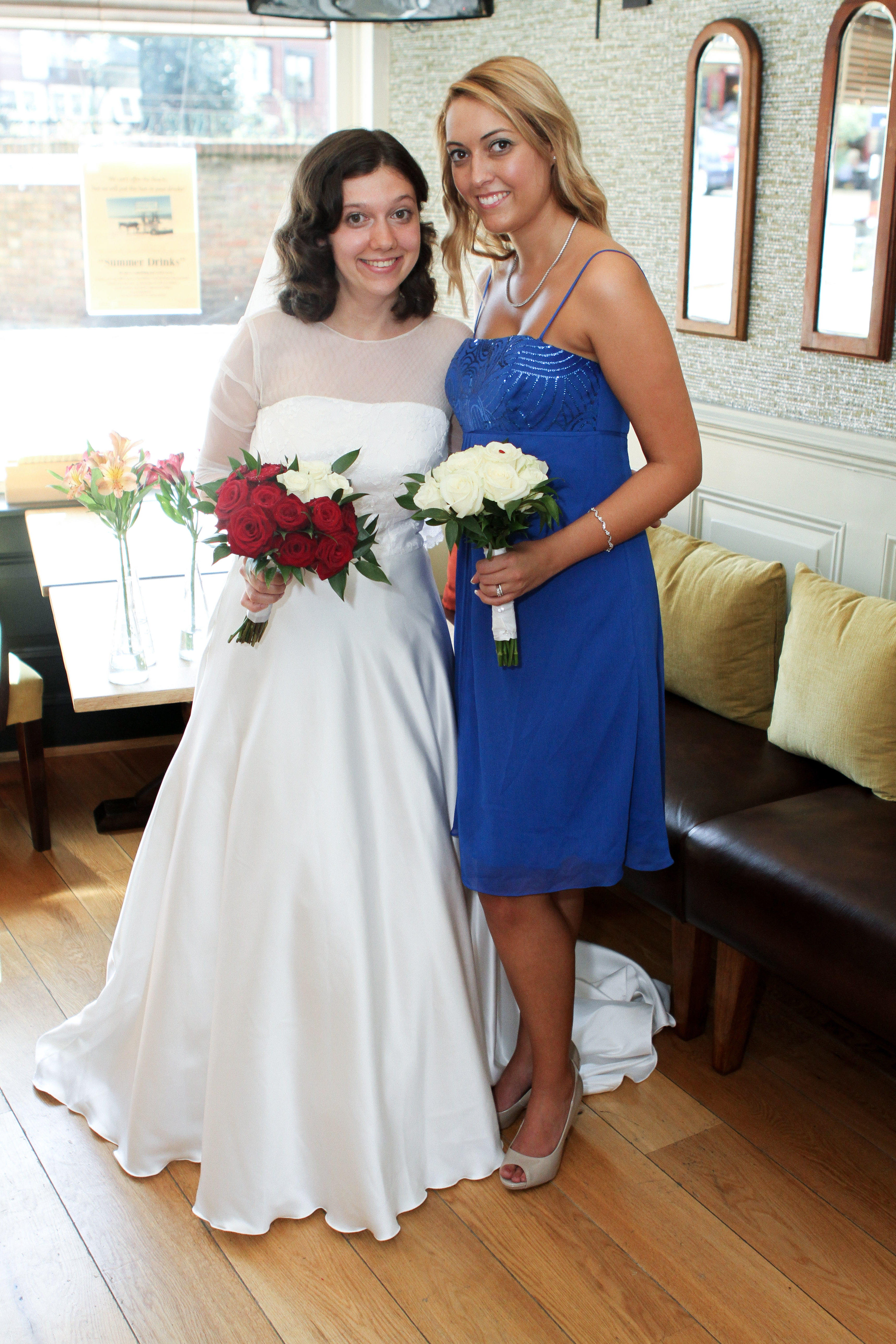 Tatyana in her wedding dress, smiling alongside bridesmaid, Laura