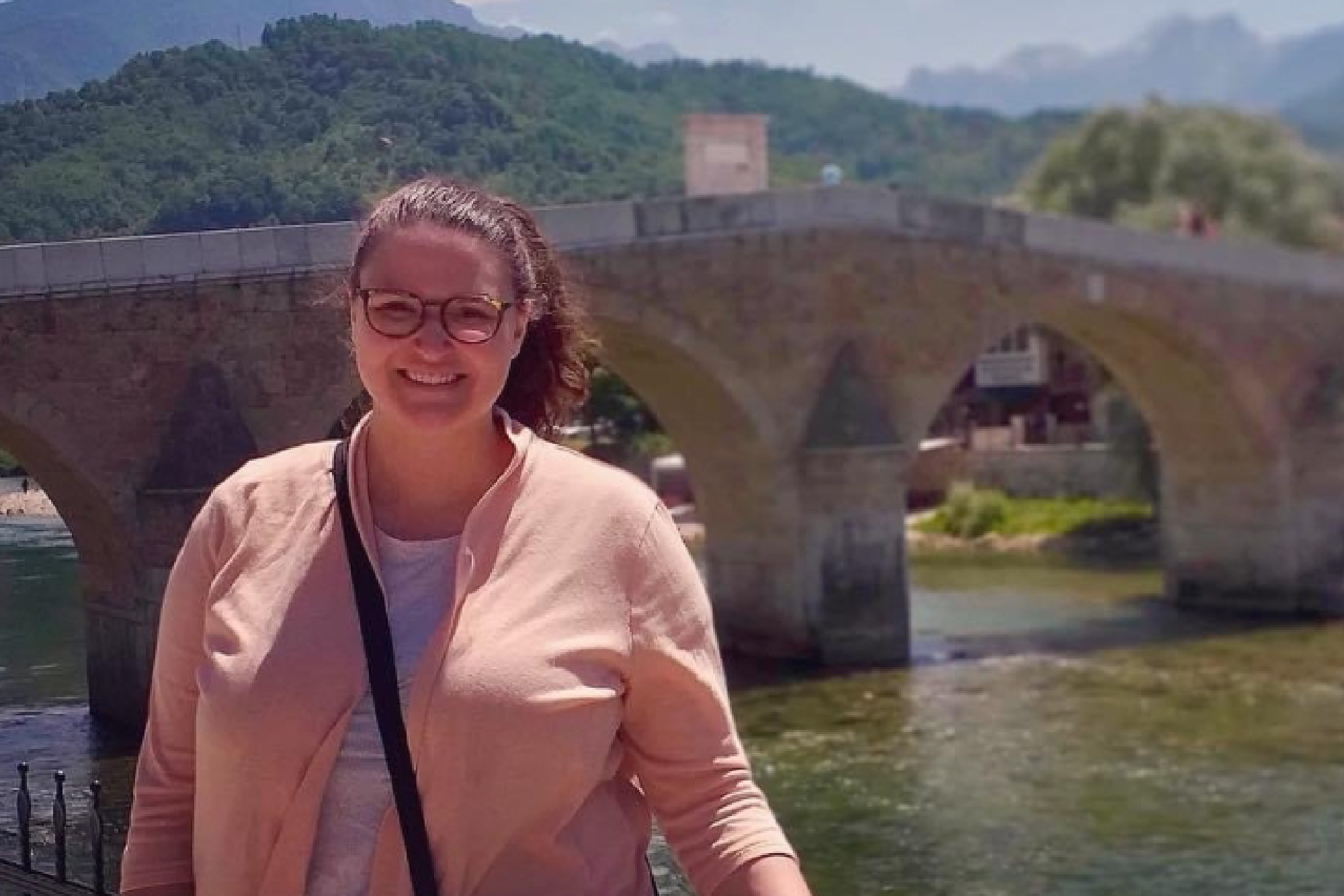 Study abroad participant posing in front of a bridge in a distant city 