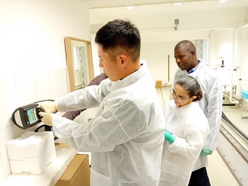Three scientists observe a device demonstration