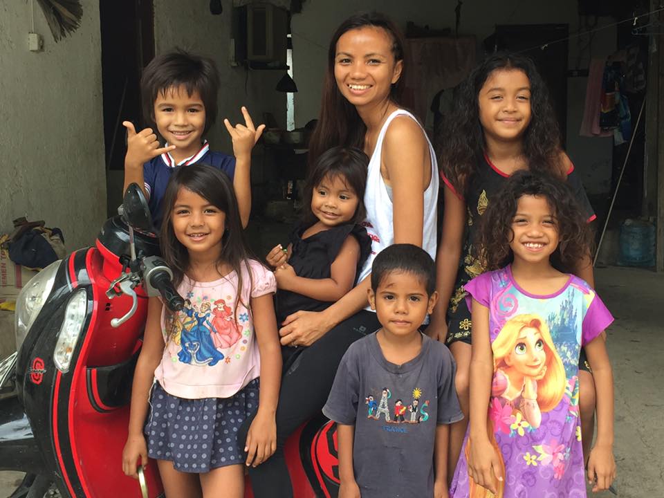 Raina smiles while sitting on a motorized scooter, surrounded by six of her young brothers and sisters.