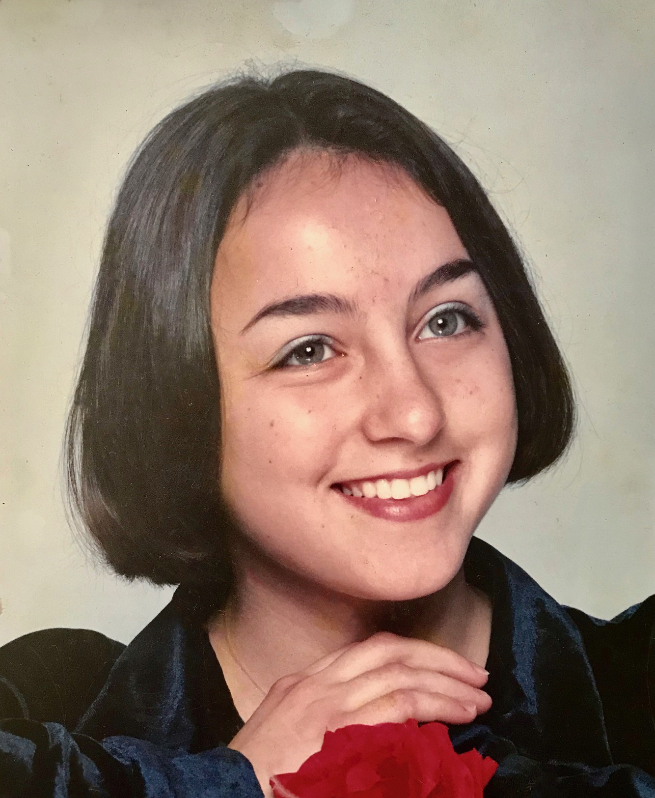 A school portrait of Anush when she was on the FLEX program, with a short hair cut, holding a flower in front of her.