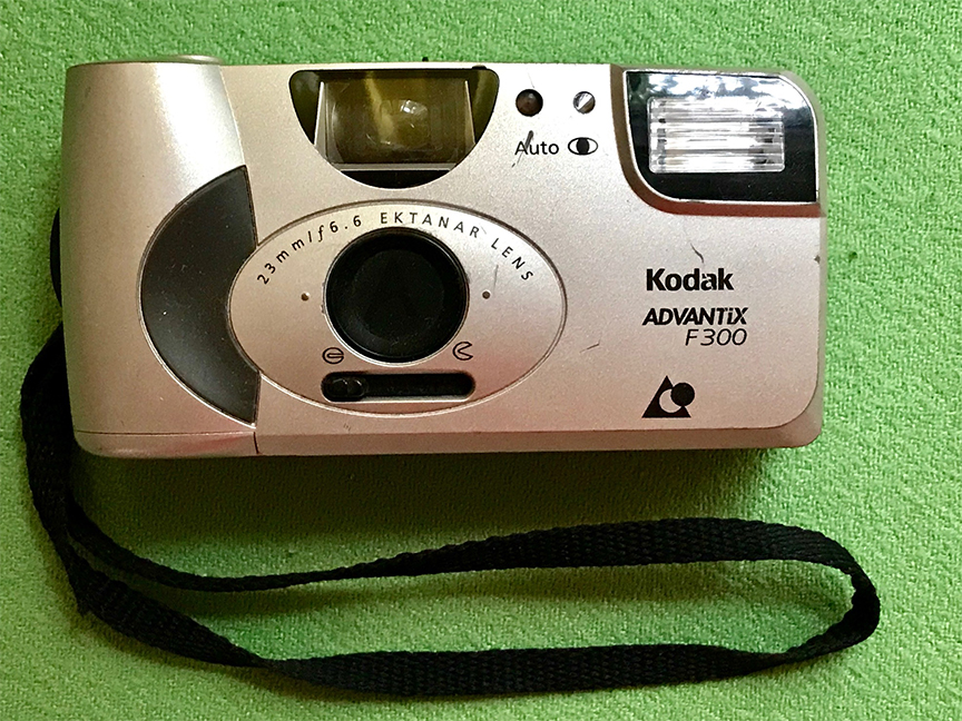 Anush's first camera, a panoramic Kodak 23 mm, in gold, sits on a background of green.