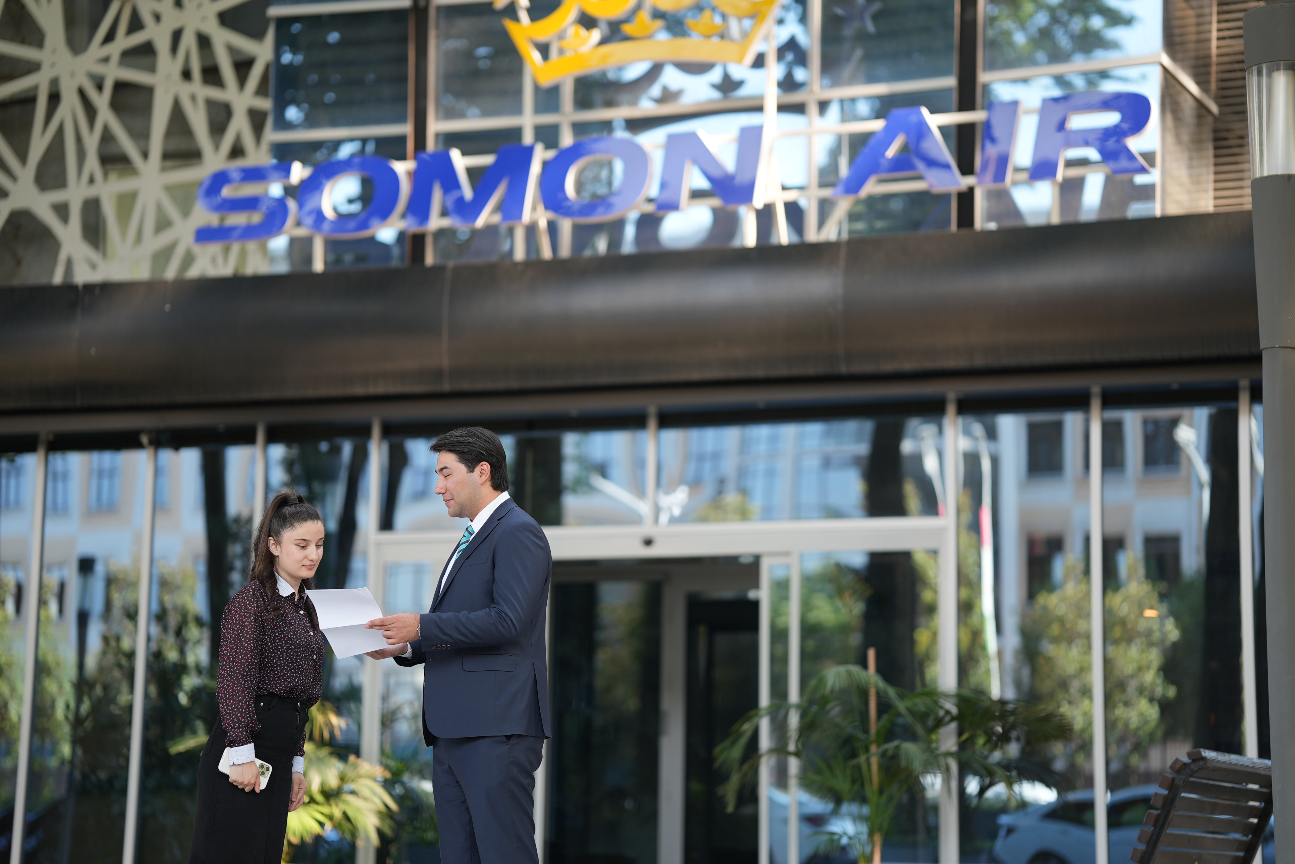 Two people hold piece of paper in front of Somon Air