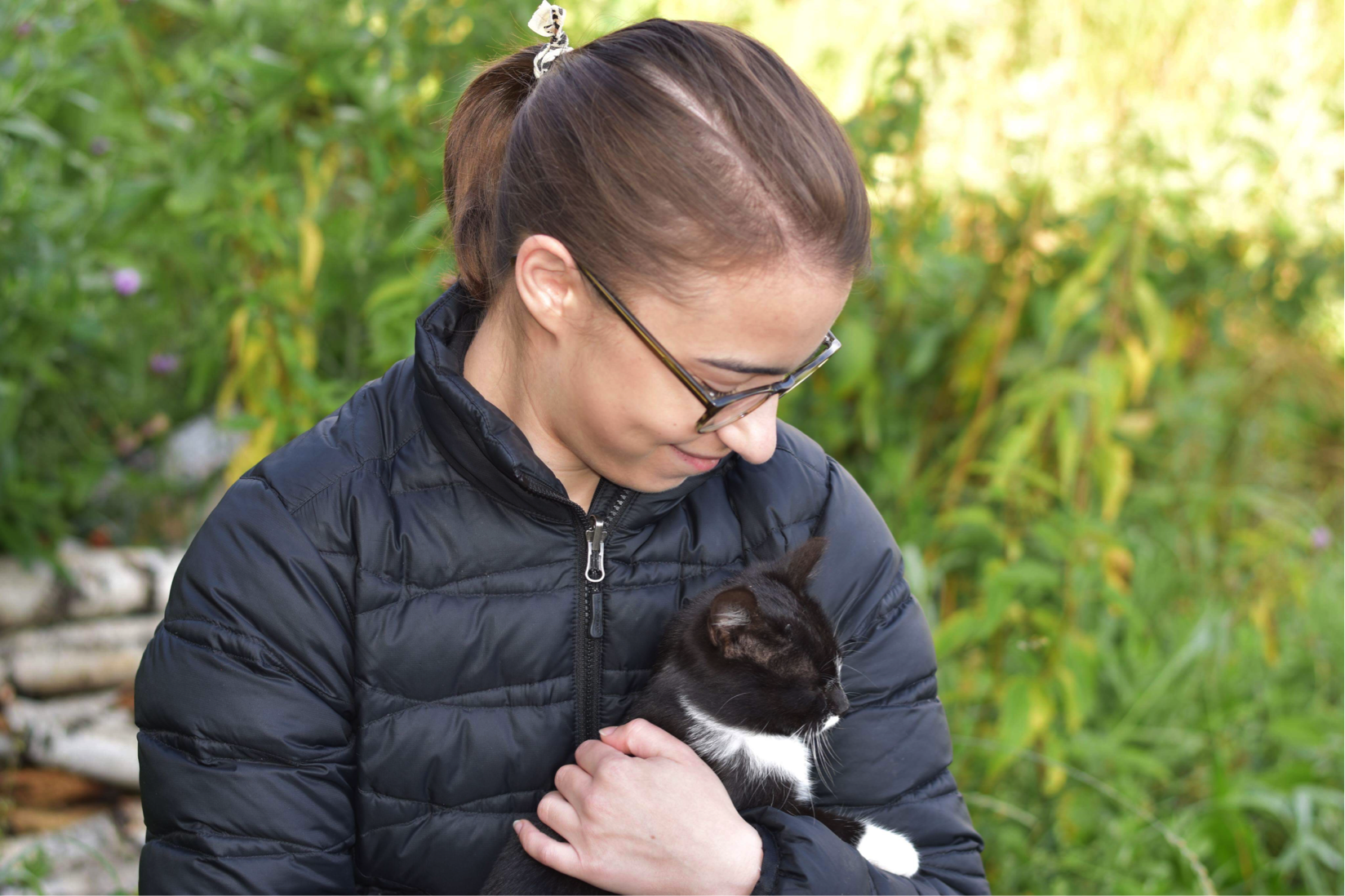 Isabella cuddles a small black and white kitten