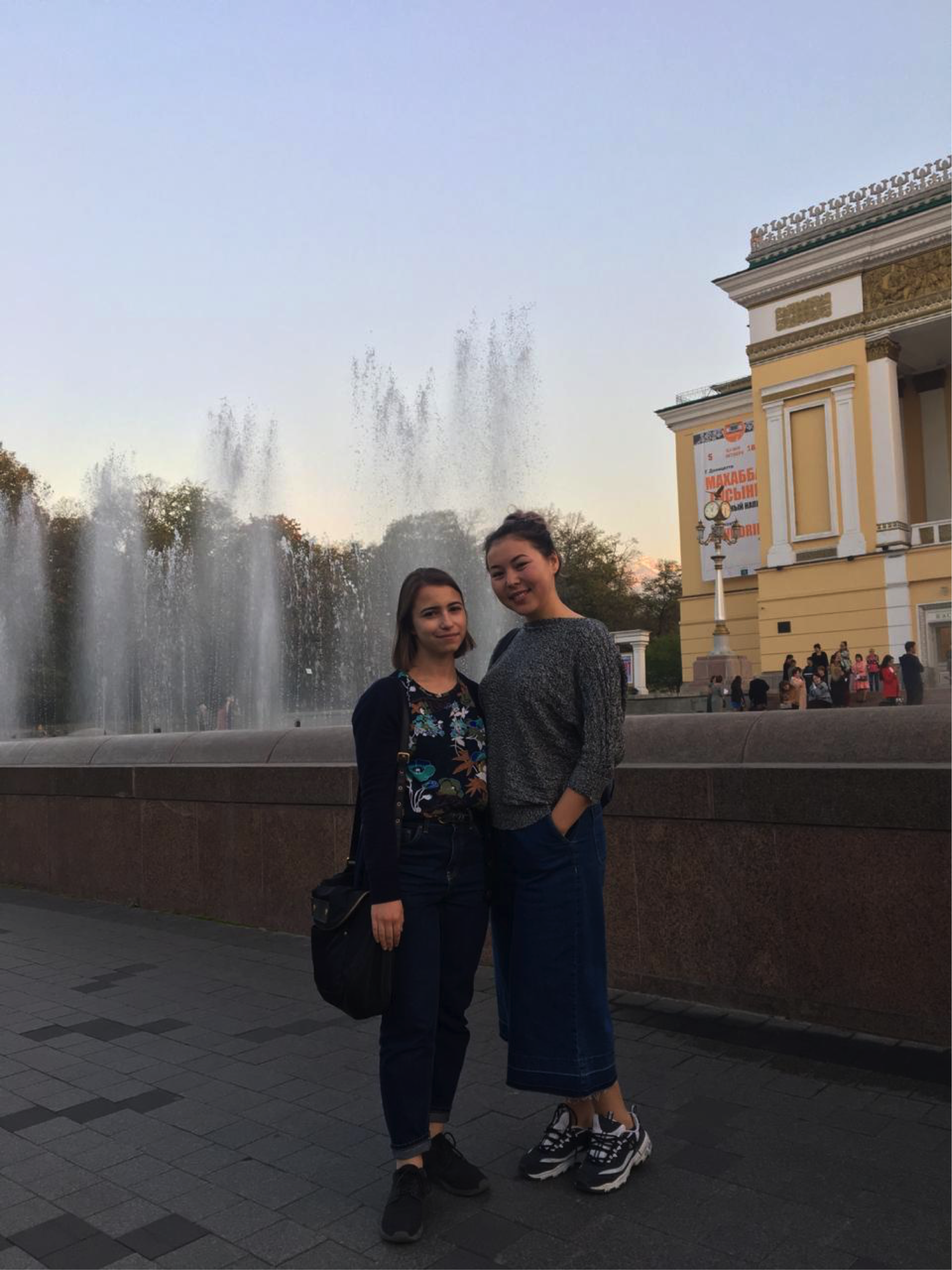 Two women stand by a water fountain