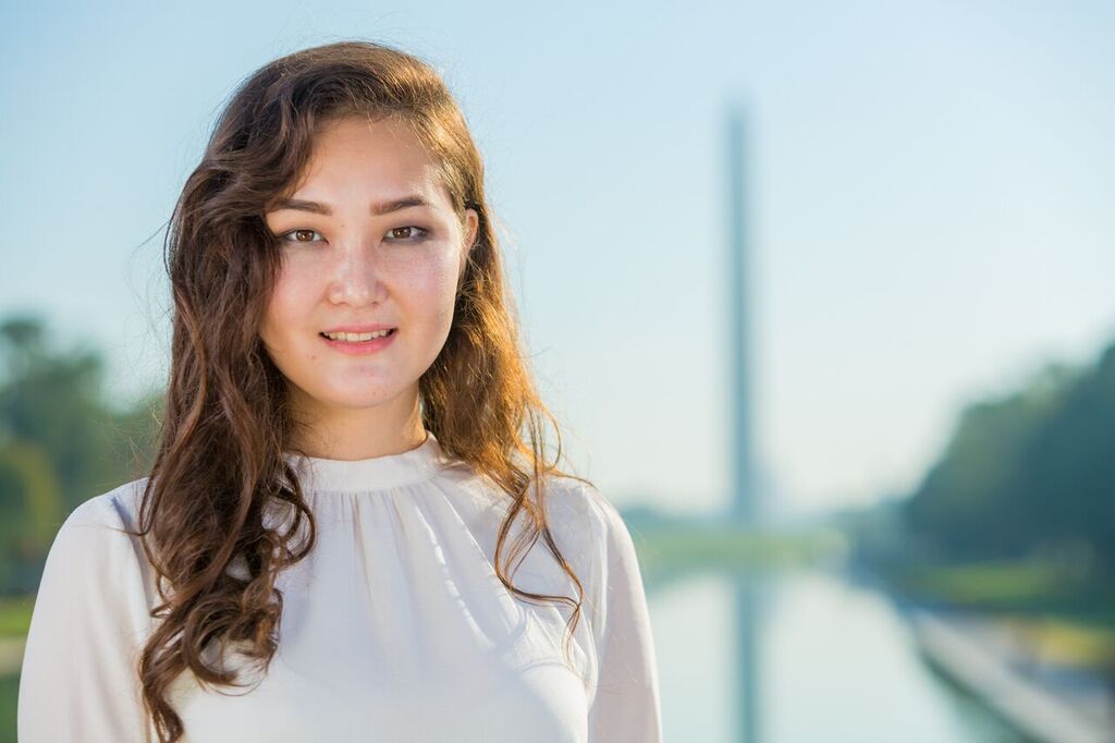 Headshot of Nazerke, in professional attire, with the Washington Monument in the background.