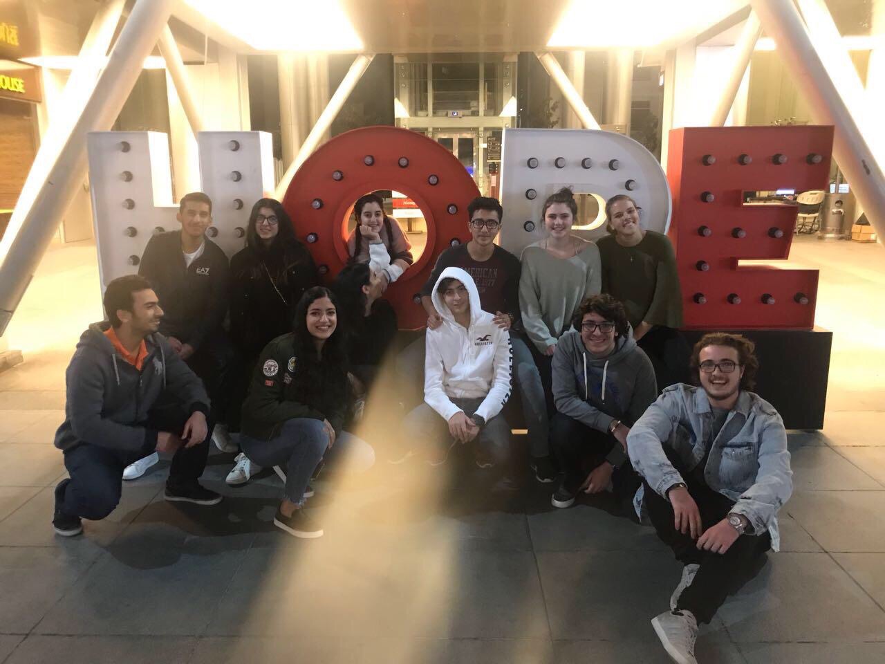 Phoebe Rossman poses with a group of friends in front of large 3-D letters that spell HOPE.