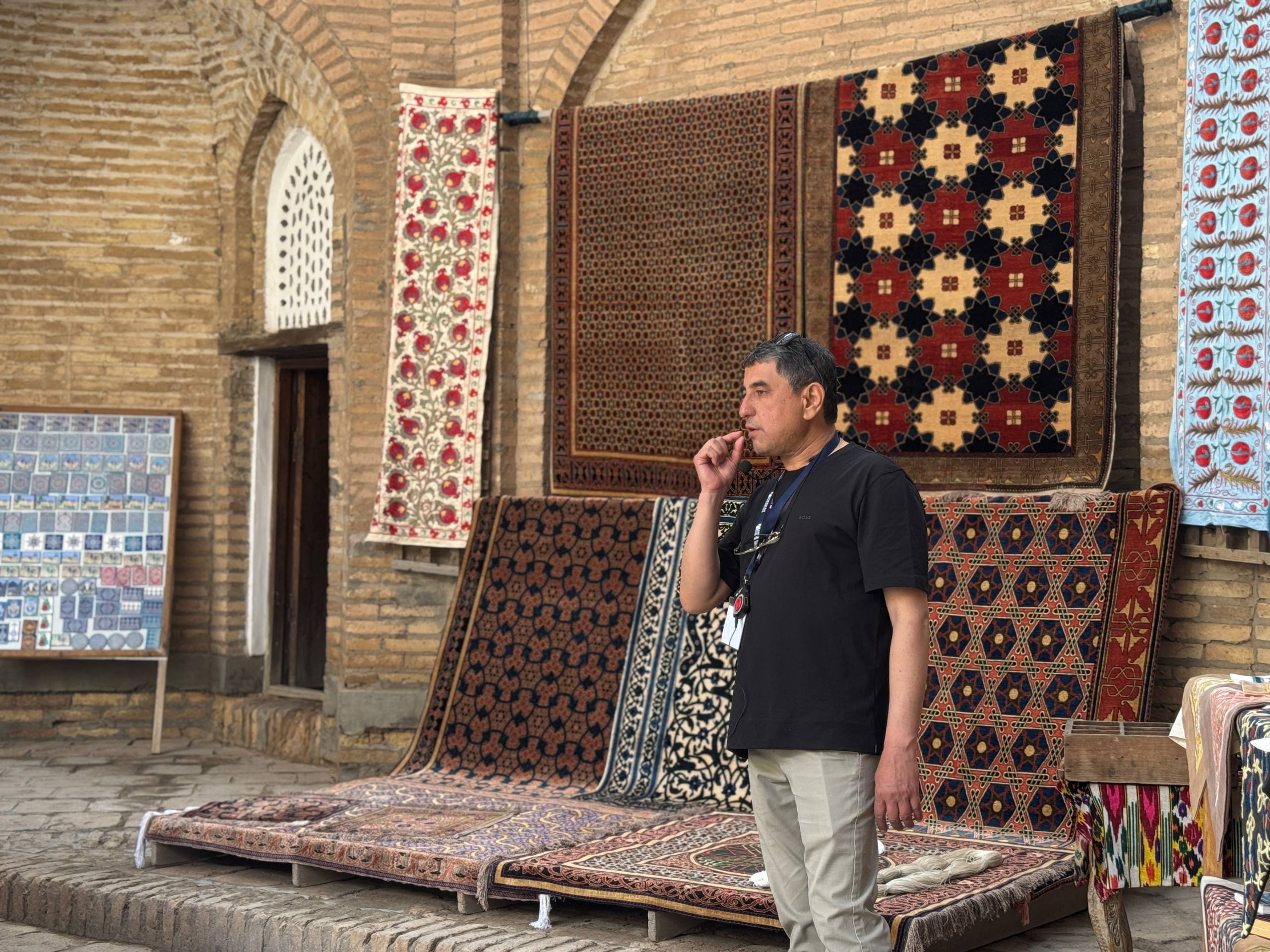 Guide speaks into headset microphone in front of colorful rugs