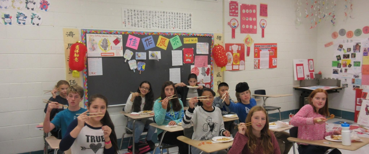 Elementary school students hold up their chopsticks to pose for a photo during Chinese language class
