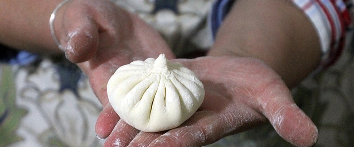 Hands holding a traditional Georgian dumpling, a khinkali