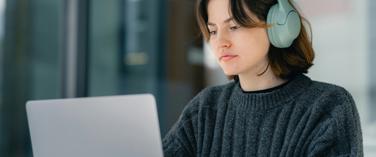 student on laptop, wearing headphones, taking test