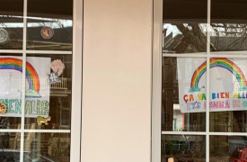Signs taped to windows, showing rainbows and reading 'Ça va bien aller,' or 'Everything will be alright!'