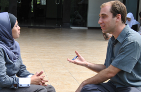 Two language partners converse while sitting on the ground