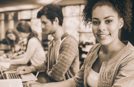 a young female student, at her computer, smiles 