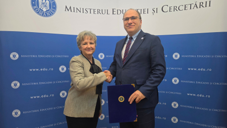 Two individuals shake hands while holding agreement